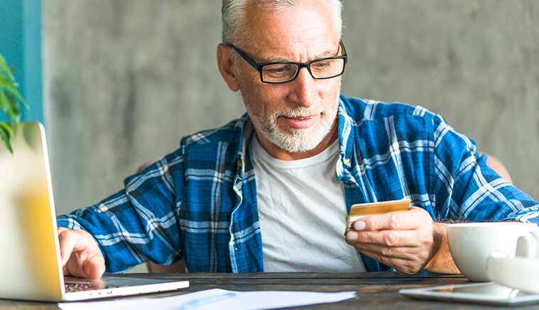 65 year old man making a purchase online with debit card