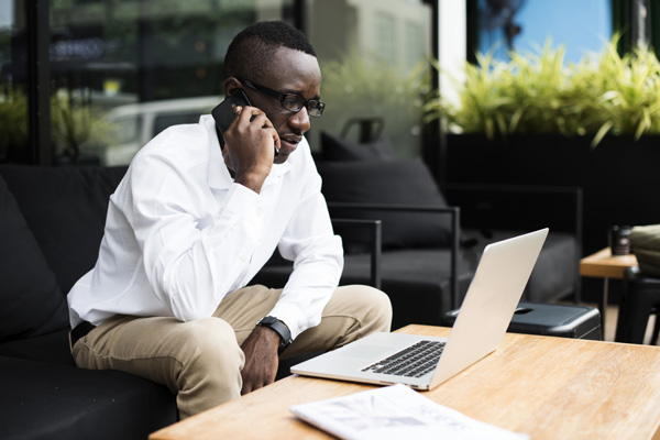 An independent contractor researches insurance on cell phone and laptop