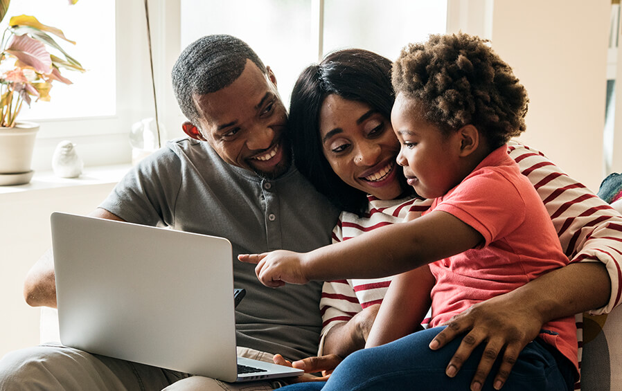 Beautiful black family of three looking at pictures on laptop