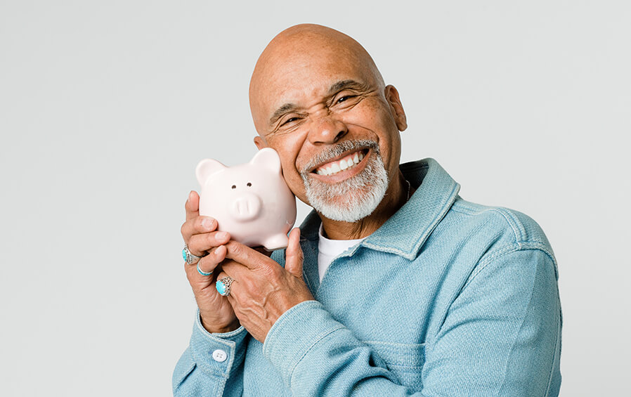 Black smiling man hugging a piggy bank