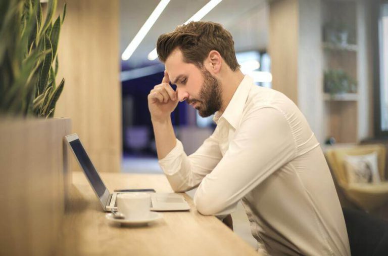man looking at laptop with a stressed out expression worried about not having accident insurance