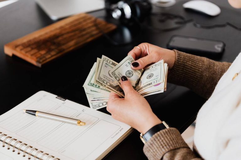 Person sitting counting money in front of a notebook