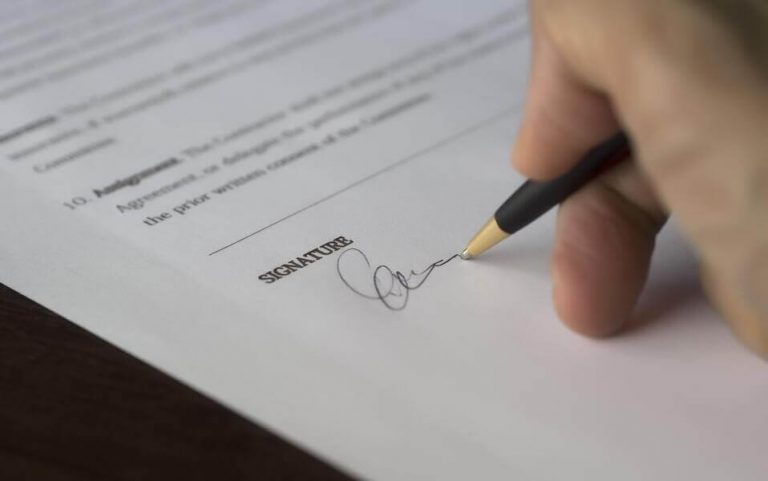 Person signing their signature on purchase agreement.