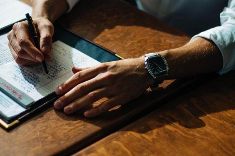 Man writing down expenses on notepad.