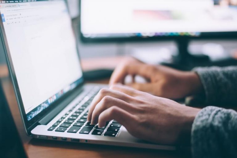 Close-up of software engineer freelancer typing on laptop.