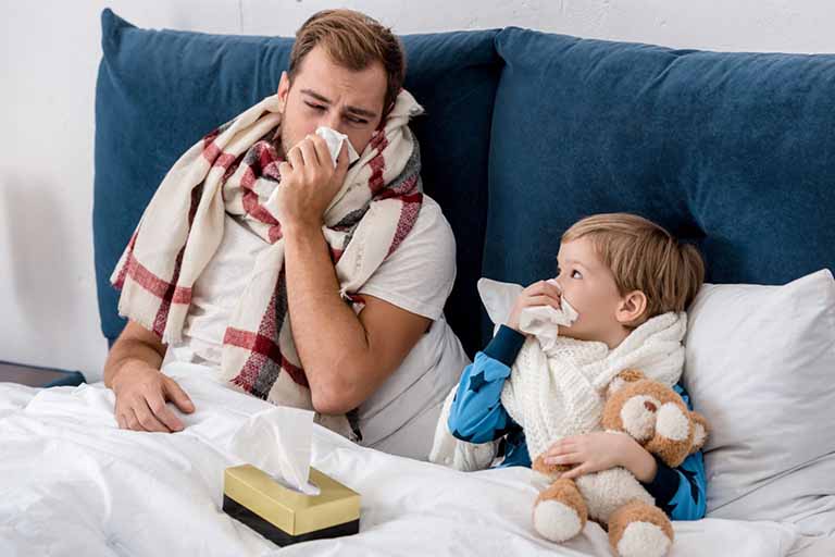 Self employed father in bed sick with his sick son