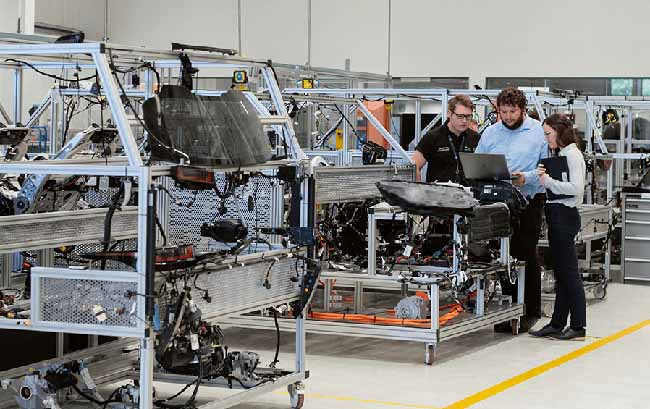 Two men and a female looking at a console in a manufacturing facility